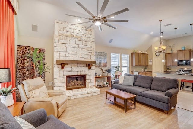 living room featuring ceiling fan with notable chandelier, light wood-type flooring, a stone fireplace, and lofted ceiling