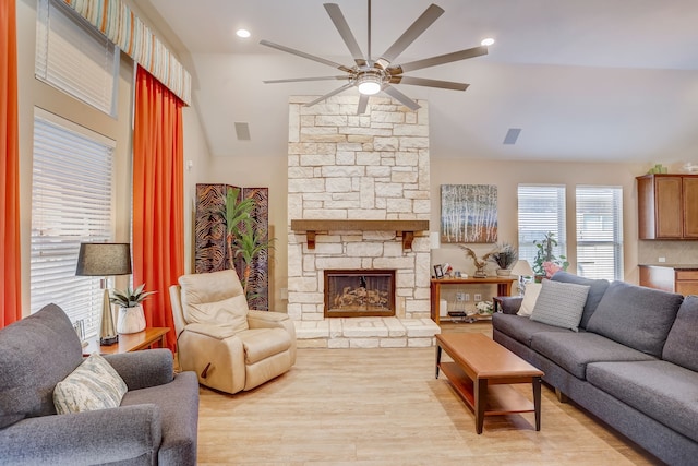 living room with ceiling fan, a fireplace, vaulted ceiling, and light wood-type flooring