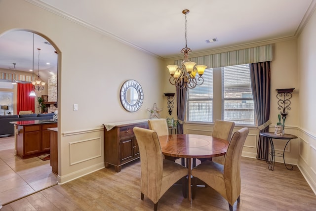 dining area featuring crown molding, light hardwood / wood-style floors, and a notable chandelier