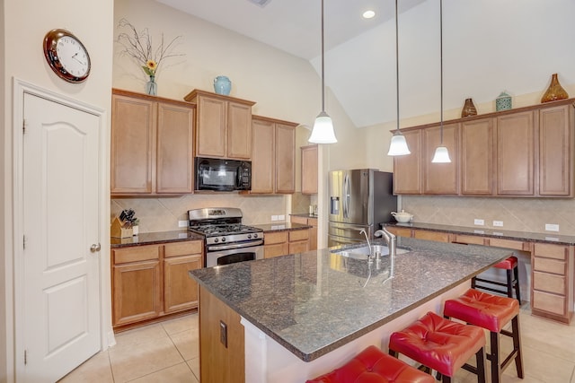 kitchen featuring sink, stainless steel appliances, pendant lighting, a breakfast bar area, and a center island with sink