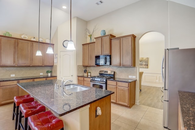 kitchen featuring backsplash, a kitchen breakfast bar, sink, an island with sink, and stainless steel appliances