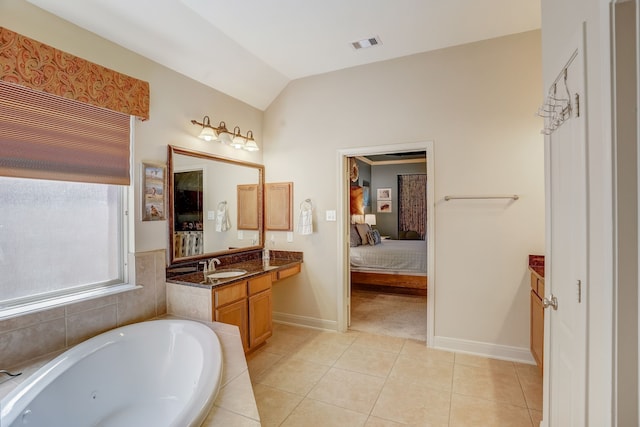 bathroom featuring tile patterned flooring, vanity, tiled bath, and vaulted ceiling