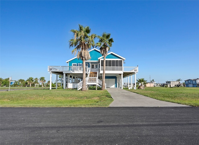 coastal home featuring a front yard, a garage, and covered porch