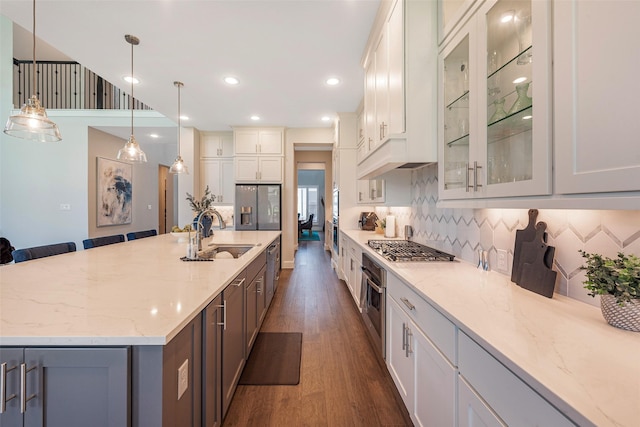 kitchen with decorative light fixtures, sink, white cabinets, dark hardwood / wood-style flooring, and backsplash