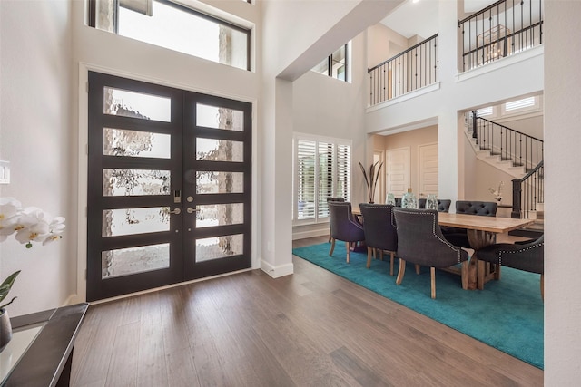 foyer entrance featuring french doors, dark wood-type flooring, and a high ceiling