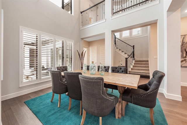 dining area featuring a towering ceiling and hardwood / wood-style floors