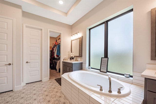 bathroom with vanity, tile patterned flooring, and a relaxing tiled tub