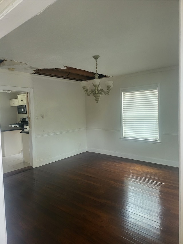 unfurnished room featuring ornamental molding, dark hardwood / wood-style floors, and an inviting chandelier