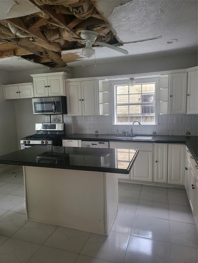 kitchen with appliances with stainless steel finishes, a kitchen island, light tile flooring, white cabinetry, and sink