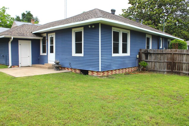 rear view of house featuring a lawn and a patio