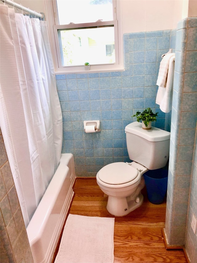 bathroom featuring tile walls, toilet, hardwood / wood-style floors, and shower / bath combo with shower curtain