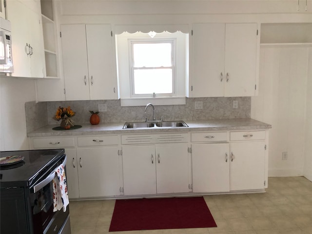 kitchen with black electric range, white cabinets, decorative backsplash, and sink