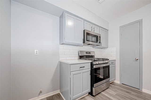 kitchen with decorative backsplash, appliances with stainless steel finishes, and light hardwood / wood-style floors