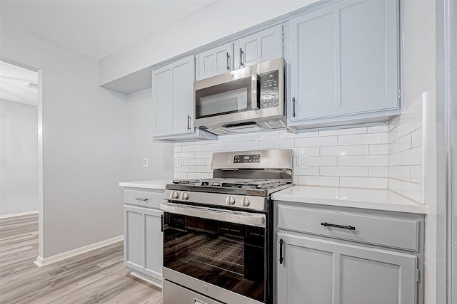 kitchen with appliances with stainless steel finishes, tasteful backsplash, and light hardwood / wood-style flooring