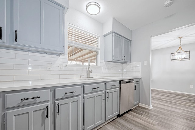 kitchen with dishwasher, sink, decorative backsplash, gray cabinets, and decorative light fixtures