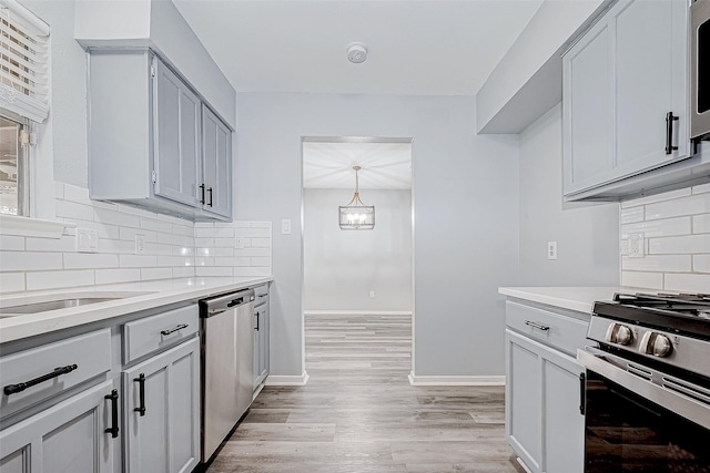 kitchen featuring backsplash, gray cabinetry, light hardwood / wood-style flooring, and appliances with stainless steel finishes