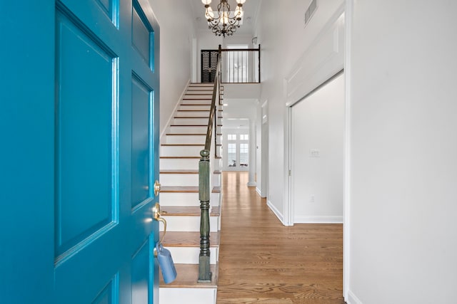 foyer featuring wood-type flooring, a high ceiling, and a notable chandelier