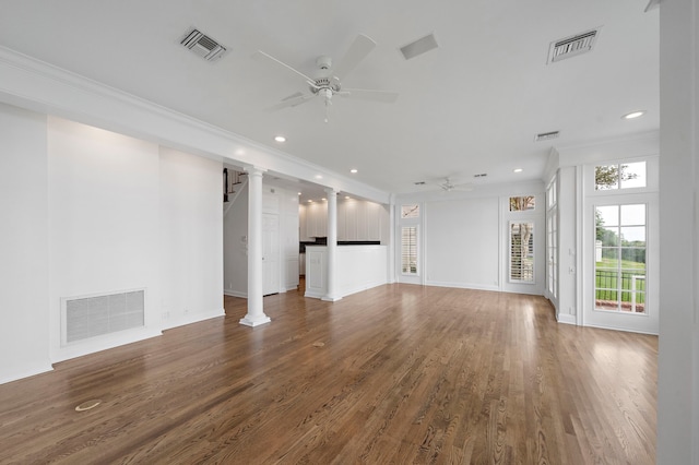 unfurnished living room with wood-type flooring, ceiling fan, crown molding, and decorative columns