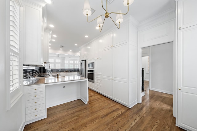 kitchen with white cabinets, crown molding, dark wood-type flooring, backsplash, and appliances with stainless steel finishes