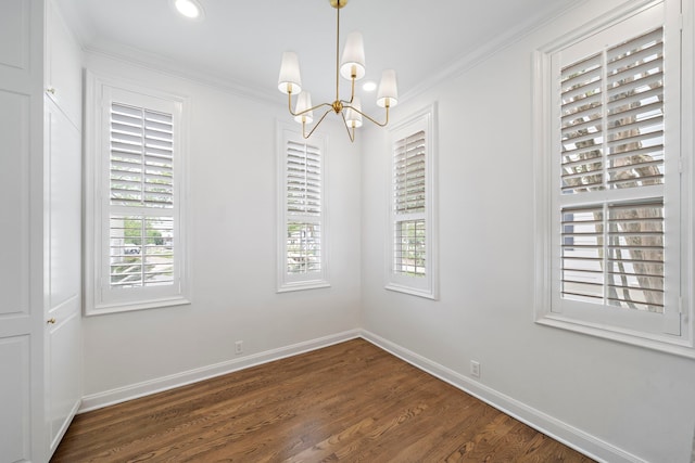 empty room featuring plenty of natural light, dark wood-type flooring, crown molding, and a chandelier