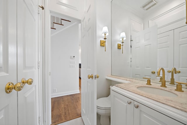 bathroom with ornamental molding, hardwood / wood-style floors, vanity, and toilet