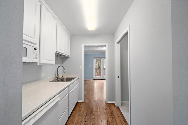 kitchen with hardwood / wood-style floors, sink, white cabinetry, and stainless steel dishwasher