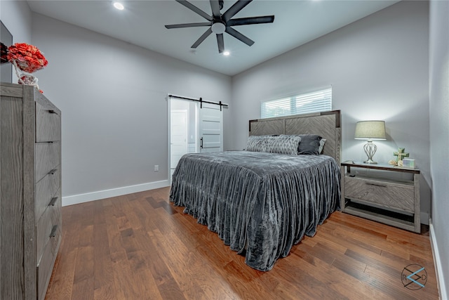 bedroom featuring a barn door, ceiling fan, and hardwood / wood-style floors