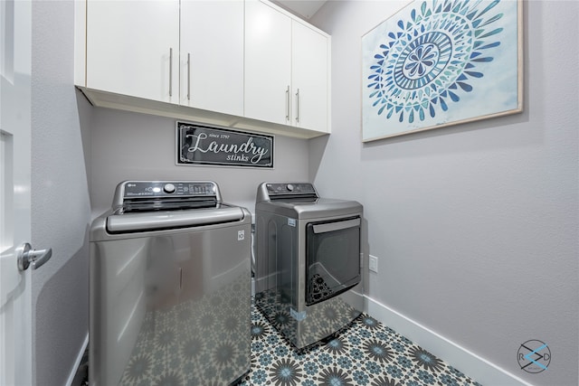 clothes washing area featuring cabinets, tile floors, and washer and clothes dryer