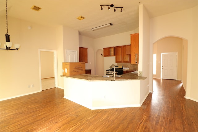 kitchen with decorative light fixtures, stainless steel range with gas stovetop, sink, hardwood / wood-style flooring, and track lighting