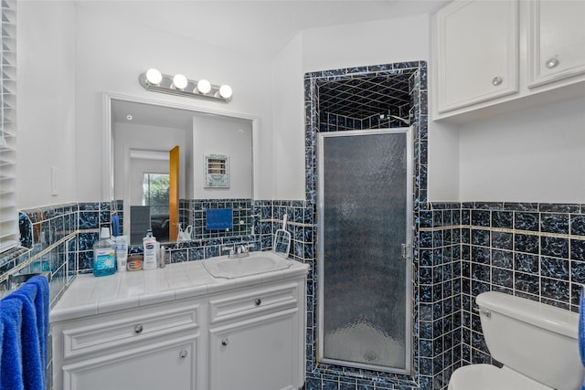 bathroom featuring vanity with extensive cabinet space, a shower with door, toilet, and tile walls