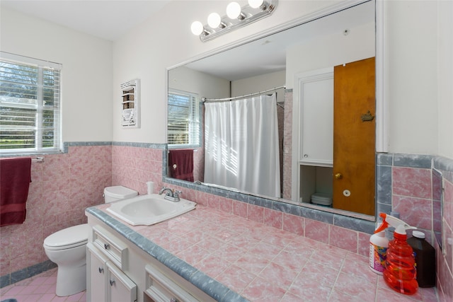 bathroom featuring tile walls, plenty of natural light, toilet, and vanity with extensive cabinet space