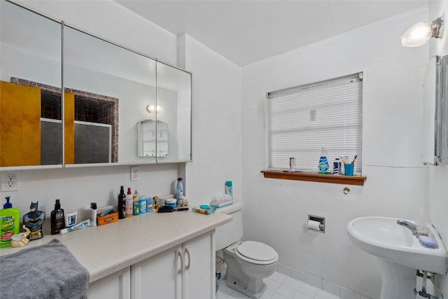 bathroom featuring toilet, tile flooring, and sink