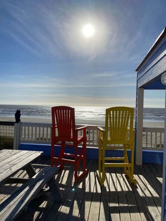 wooden deck featuring a beach view and a water view