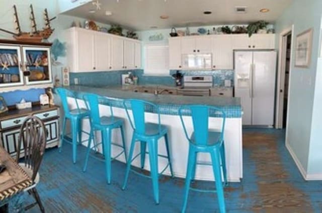 kitchen featuring backsplash, white appliances, kitchen peninsula, and white cabinetry