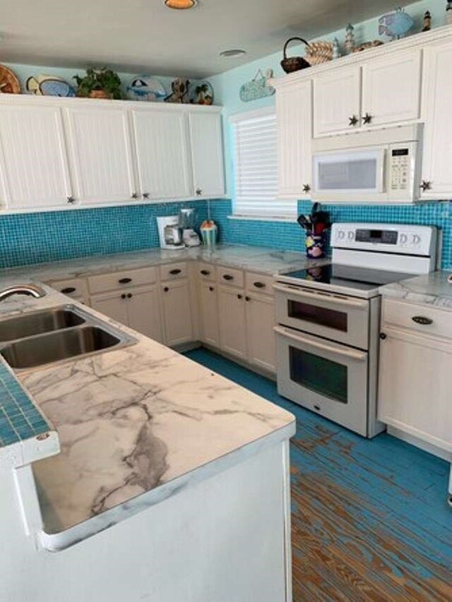 kitchen with backsplash, white appliances, sink, and white cabinetry