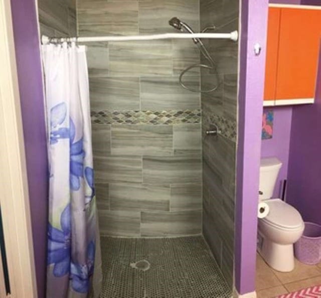 bathroom with walk in shower, tile floors, and toilet