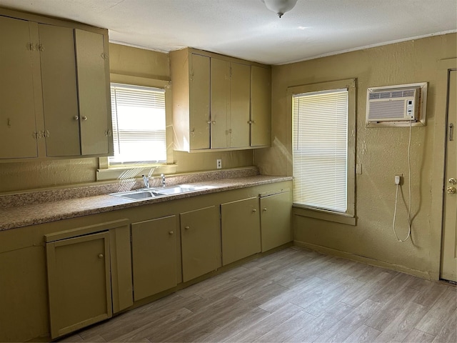 kitchen featuring a wall unit AC, sink, and light hardwood / wood-style floors