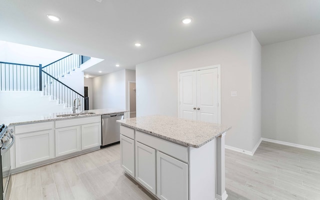 kitchen with appliances with stainless steel finishes, sink, a kitchen island, light hardwood / wood-style floors, and white cabinets