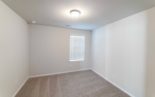 carpeted empty room with a textured ceiling