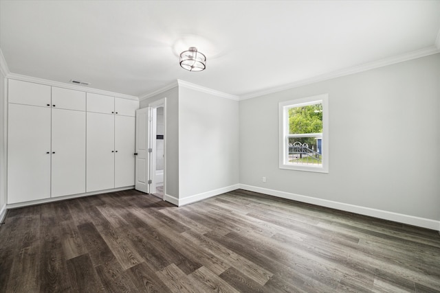 unfurnished bedroom with a closet, dark hardwood / wood-style floors, and crown molding