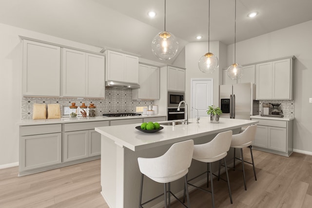 kitchen with decorative backsplash, sink, light wood-type flooring, and appliances with stainless steel finishes