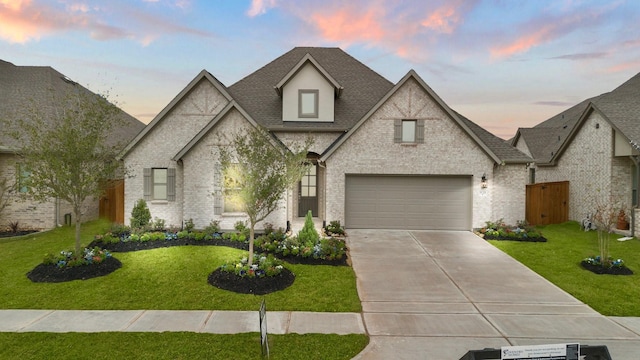 french country inspired facade with a yard and a garage