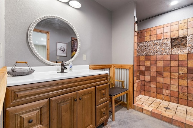 bathroom with tiled shower and vanity