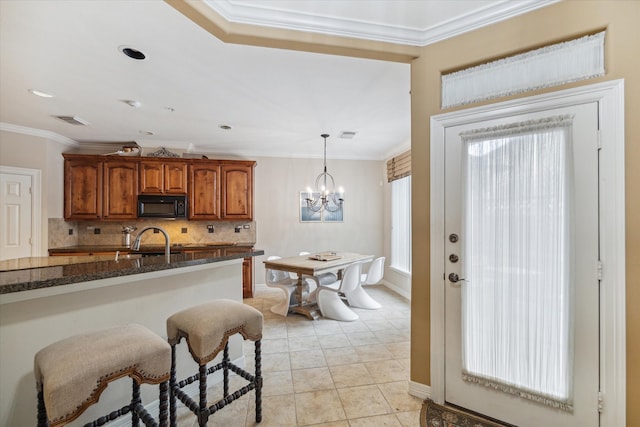 kitchen featuring decorative light fixtures, backsplash, crown molding, light tile flooring, and a chandelier