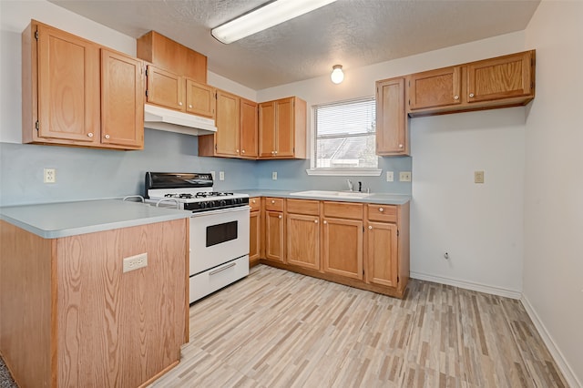 kitchen with white gas range oven, sink, light hardwood / wood-style floors, and a textured ceiling