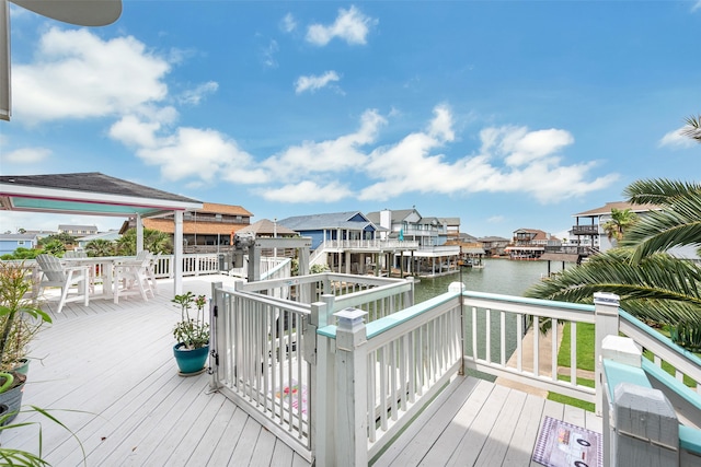 wooden terrace featuring outdoor dining area, a water view, and a residential view