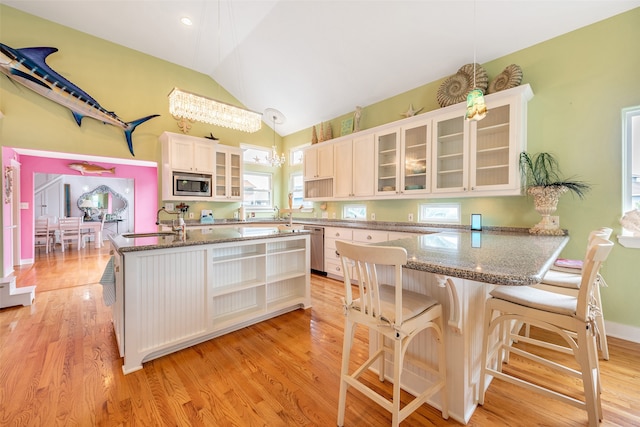 kitchen featuring stone countertops, light wood-style flooring, stainless steel appliances, vaulted ceiling, and open shelves