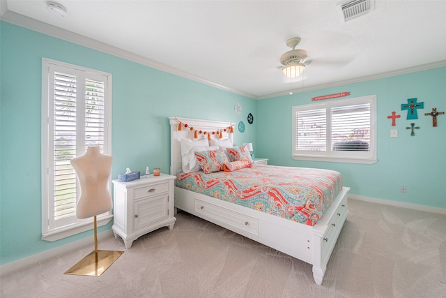 bedroom with ceiling fan, light colored carpet, visible vents, baseboards, and ornamental molding