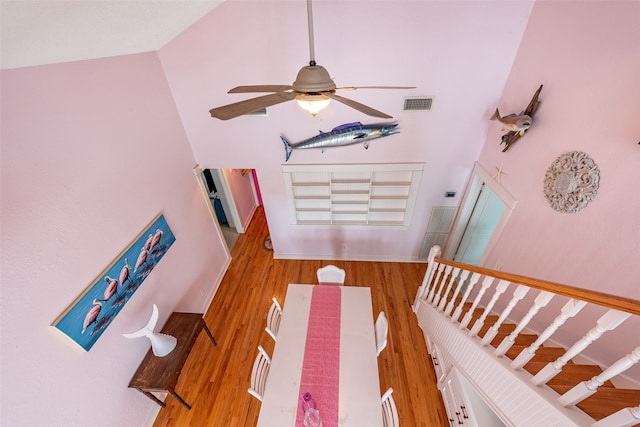 living area featuring high vaulted ceiling, a ceiling fan, visible vents, and wood finished floors