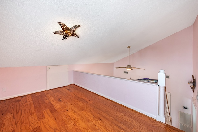 bonus room with visible vents, lofted ceiling, ceiling fan, wood finished floors, and a textured ceiling